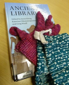 the half-finished gloves lying on top of a book on ancient libraries